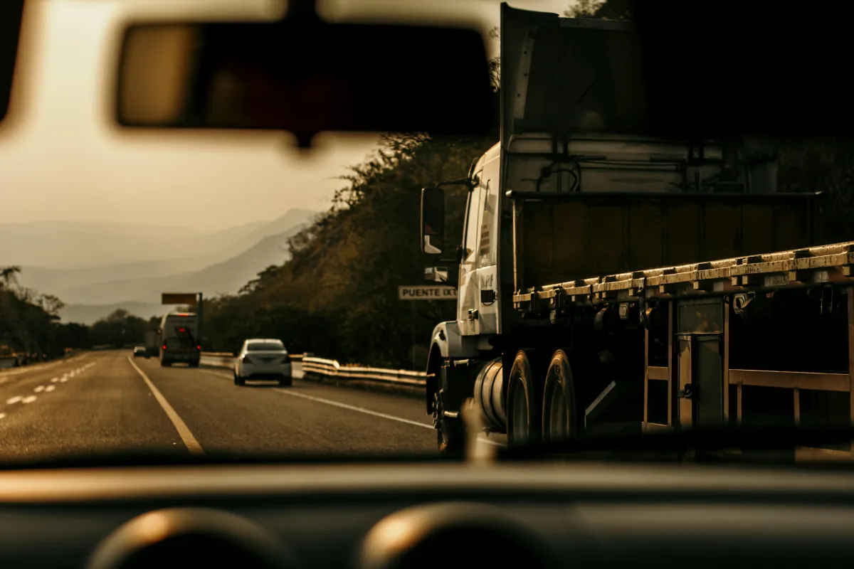 Tractocamión con semirremolque y un auto compartiendo una autopista de cuota en México